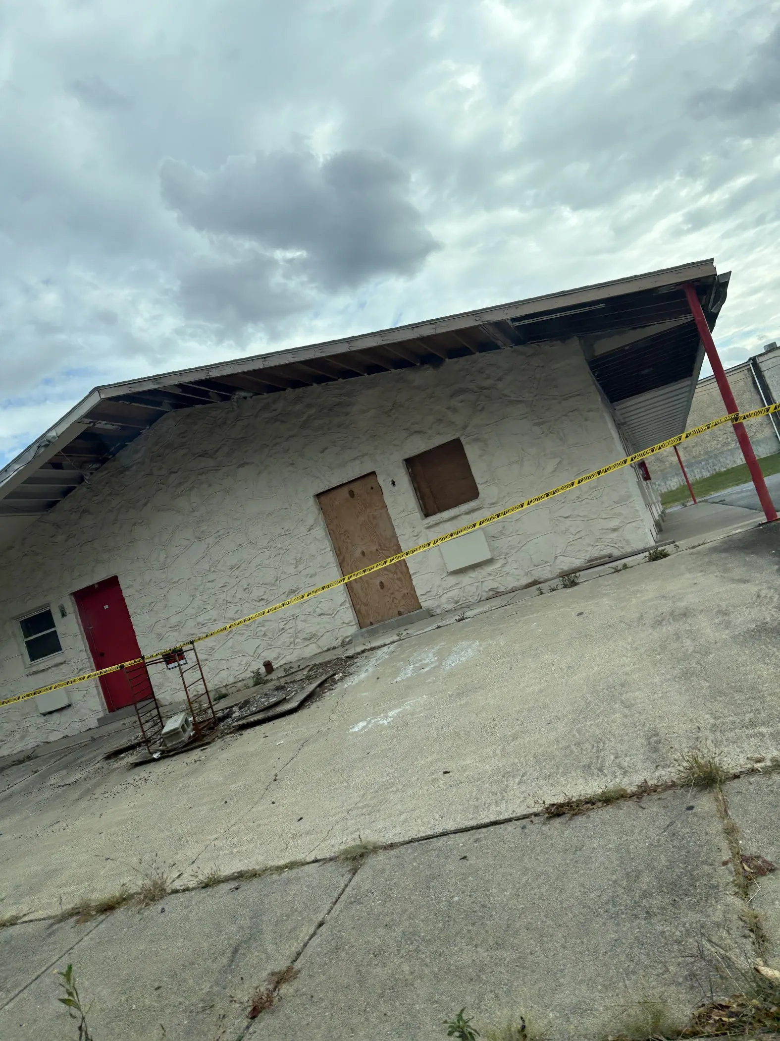 Boarded openings and exposed eaves along a low-rise masonry building.